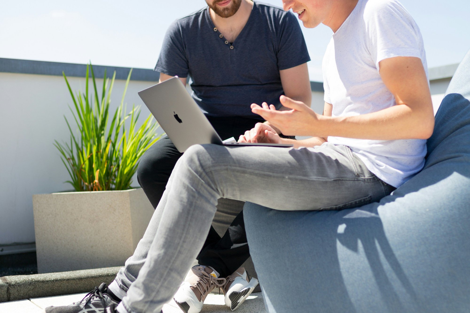 två män diskuterar framför laptop utomhus