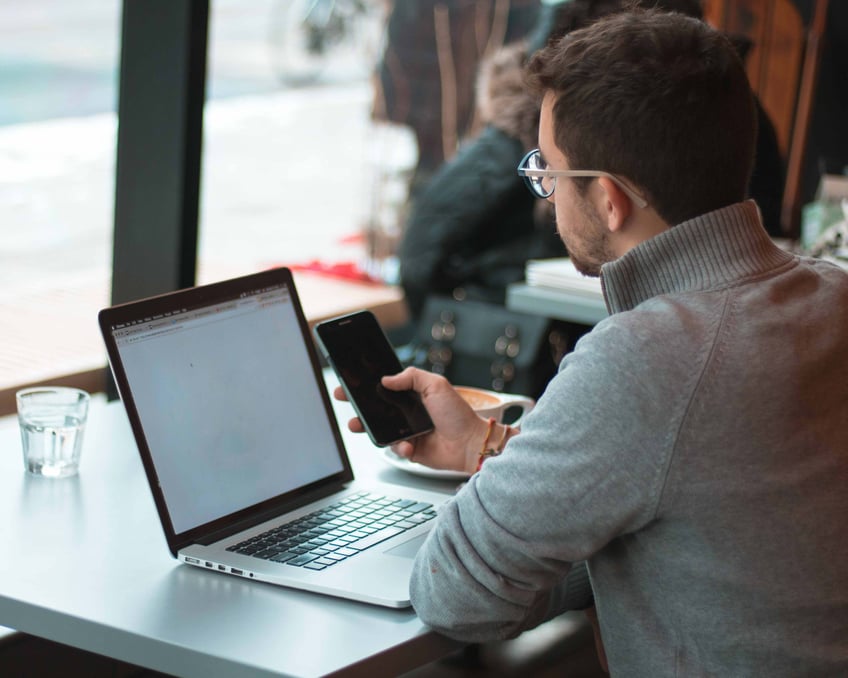 Man på cafe med laptop och mobil cybersäkerhet