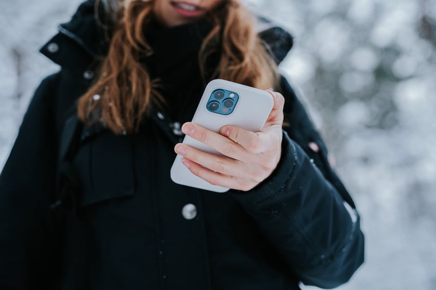 kvinna håller i mobil på vintern