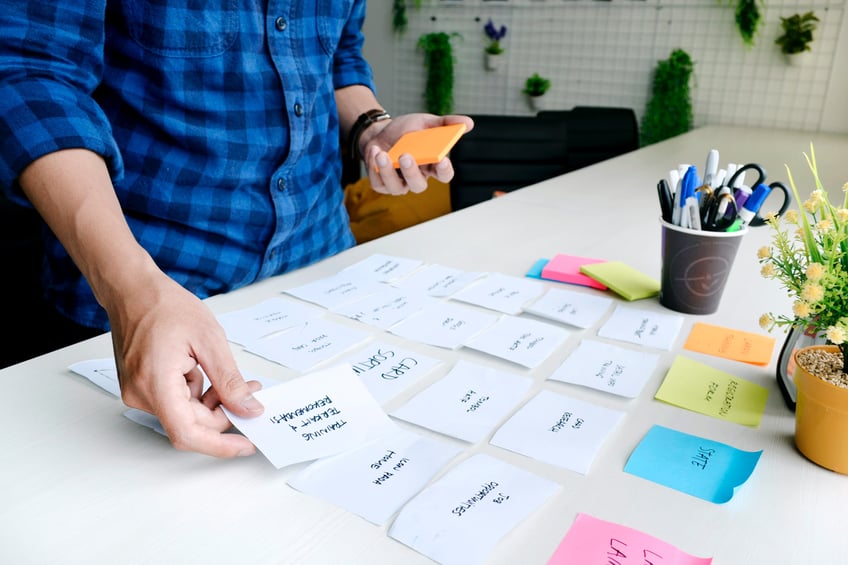 man står vid skrivbord och sorterar post it lappar