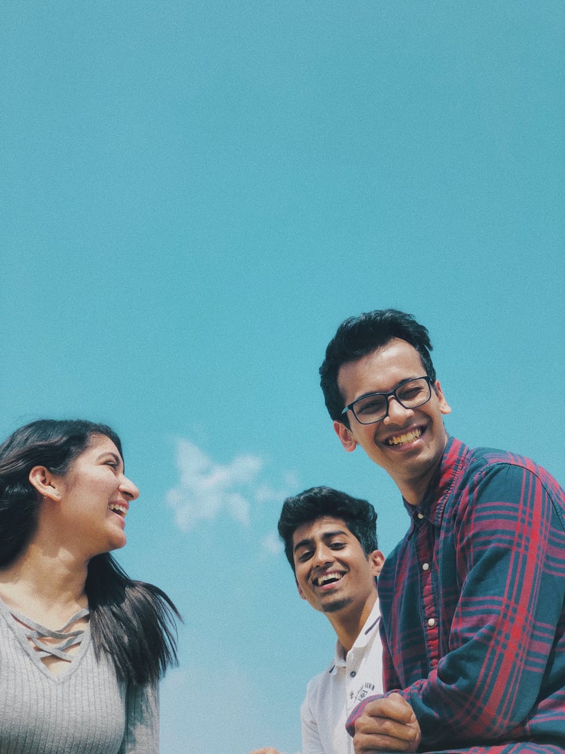 tre personer som ler framför blå himmel