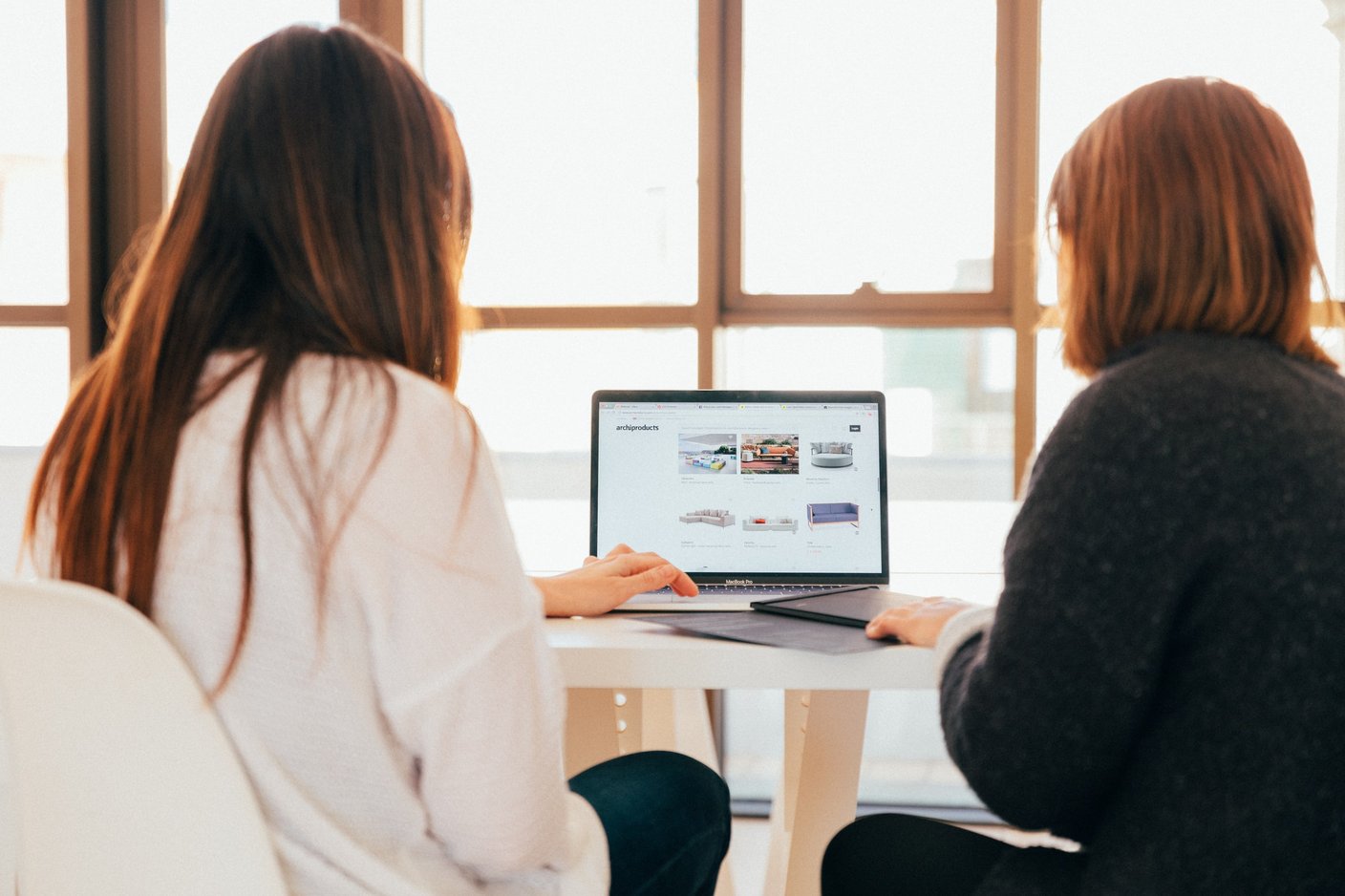 två kvinnor sitter framför en laptop